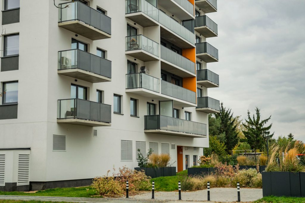 Moderner Apartmentkomplex mit Glasbalkonen und gepflegter Außenanlage.